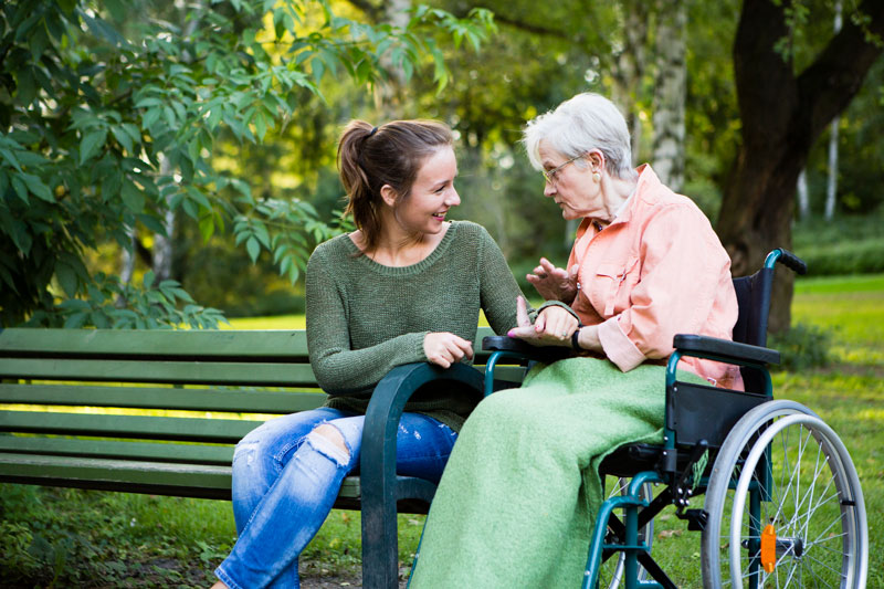 Young women and older woman enjoying chatting together in a park
