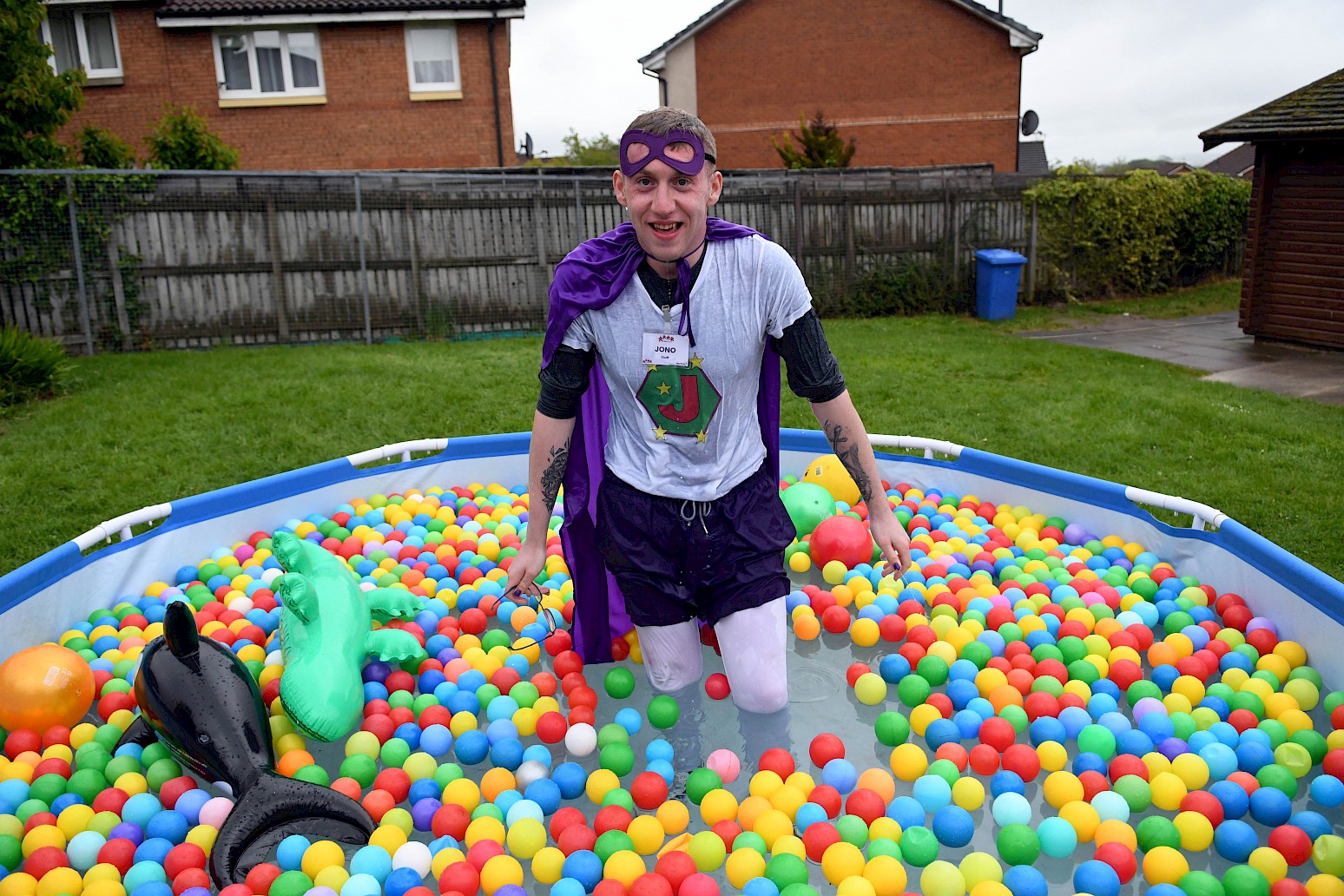 Jono outdoors in a paddling pool full of balls and inflatable toys
