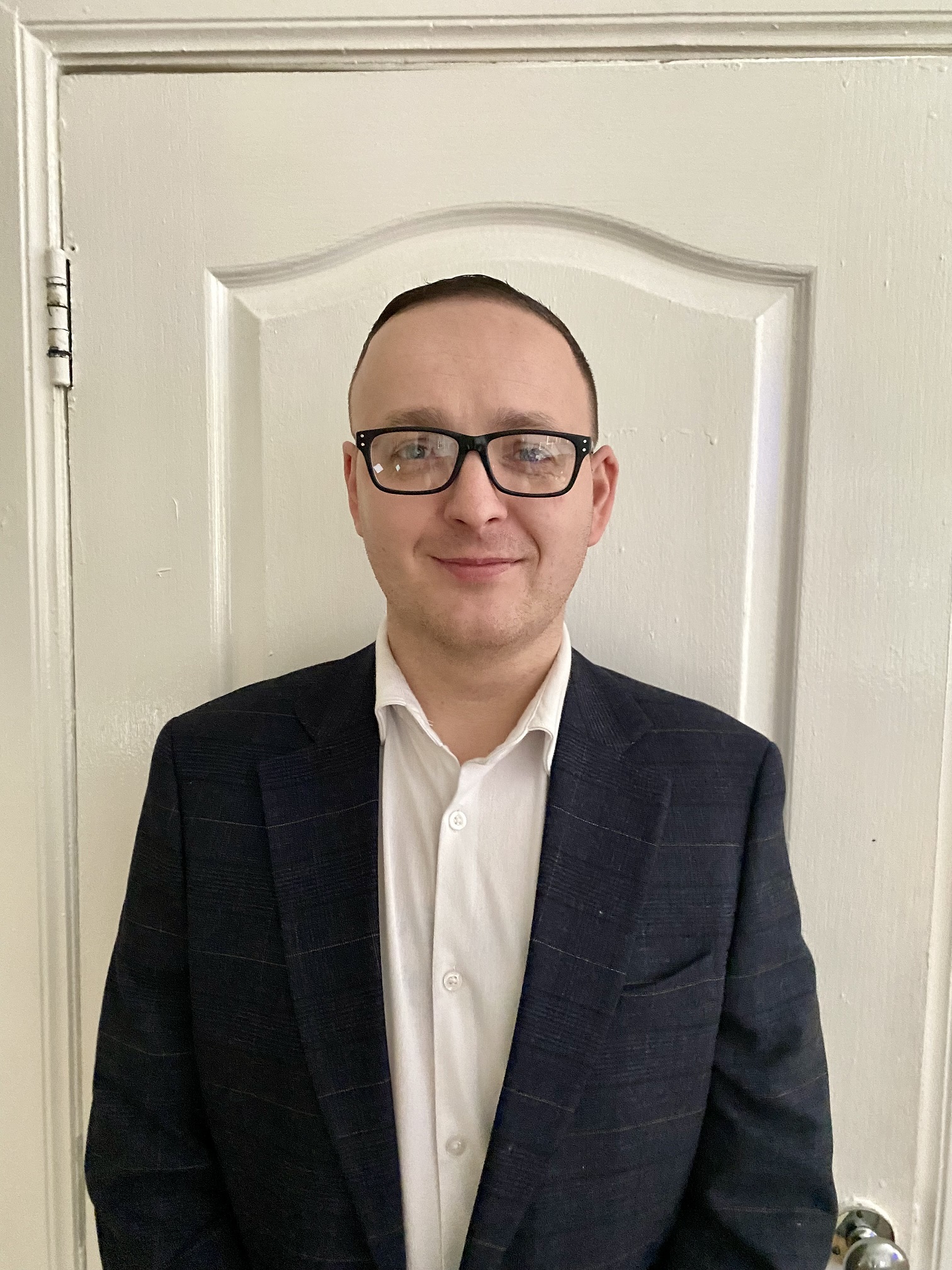 Gareth pictured inside wearing a suit and glasses